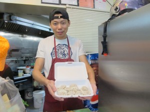 Man holding tray of dumplings.